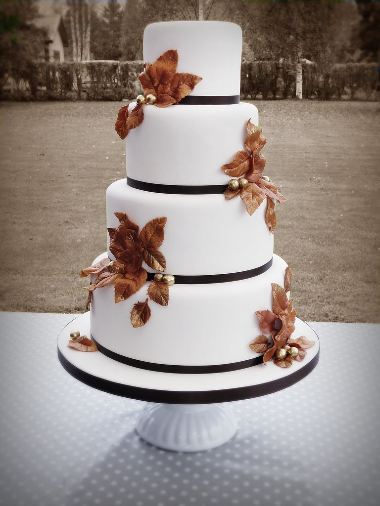 A white tiered cake trimmed with gold sugar leaves